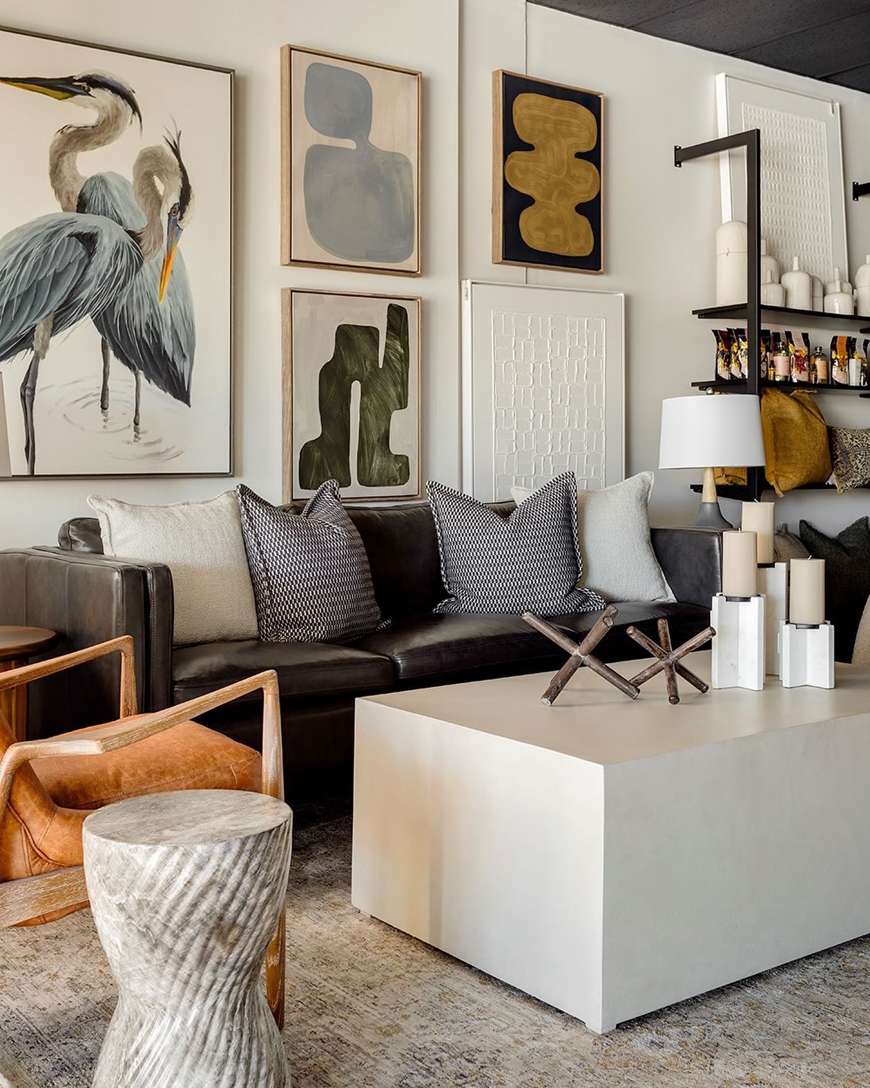 Inside the Dekor Butik showroom: a dark leather sofa with patterned cushions, framed wall art, a white coffee table and shelves of home decor